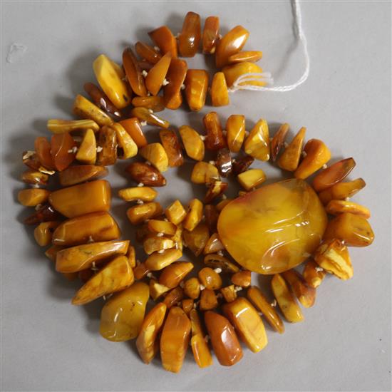 A single strand jagged amber necklace and an amber brooch, gross weight 104 grams, necklace 86cm.